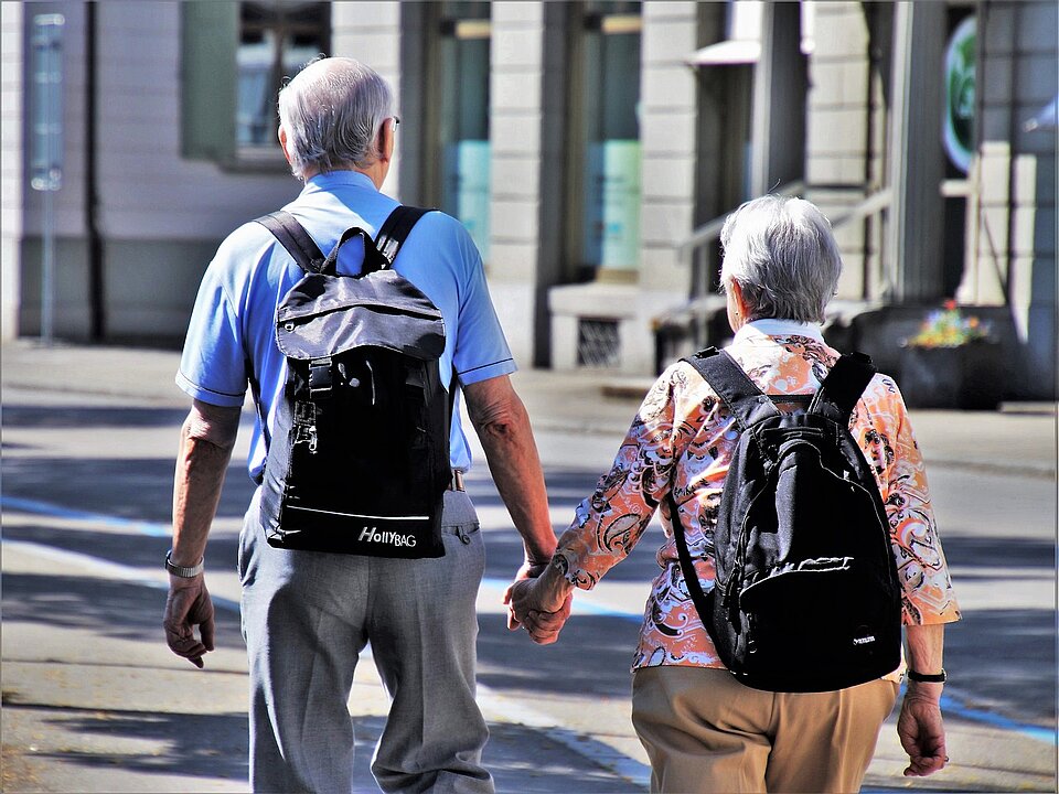 zwei ältere Menschen gehen Hand in Hand